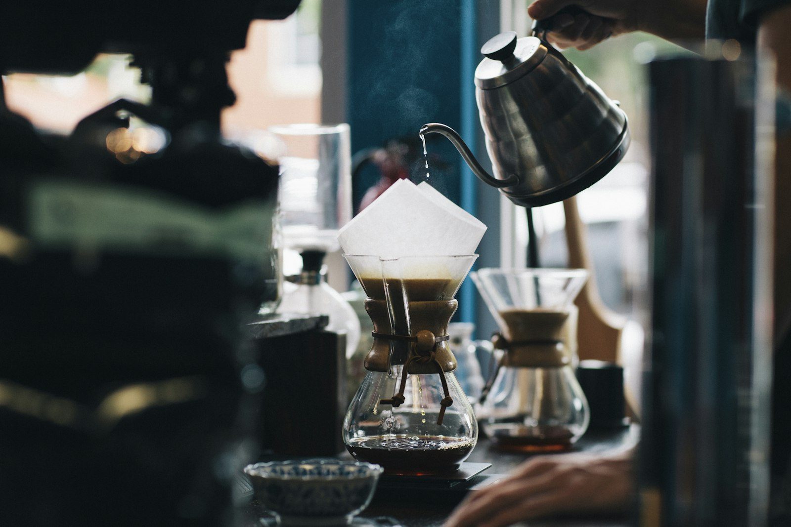 Barista Kopi Tigarasa menyeduh kopi pour-over dengan teliti di bar kayu