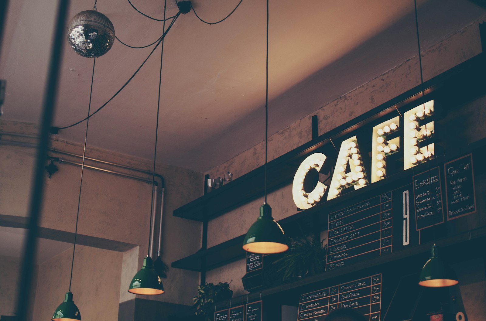 Suasana interior kedai Kopi Tigarasa yang temaram dan hangat dengan papan nama di dinding