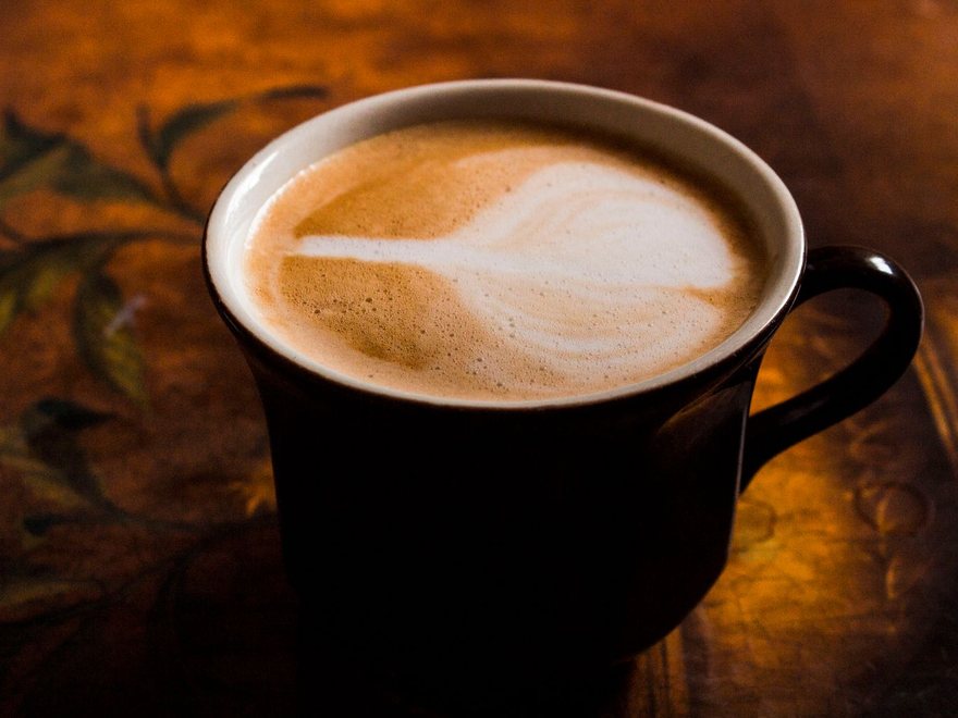 Cappuccino klasik dengan microfoam di mug hitam